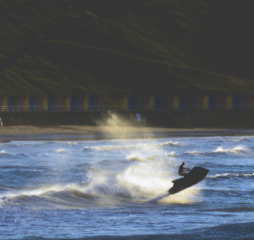 Person using a jet ski in Whitby Bay with beach huts in the distance